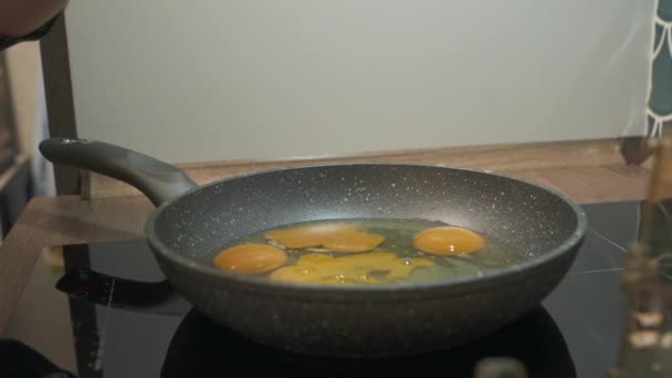 Les œufs frais se cassent dans la poêle chaude sur la cuisinière. Œufs frits dans une poêle antiadhésive. — Video