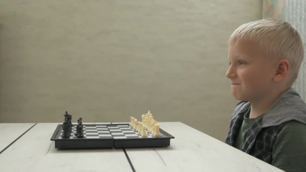Милий маленький хлопчик грає в шахи вдома . — стокове відео