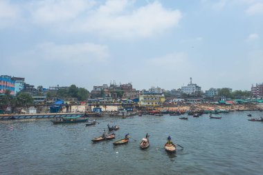 Dhaka 'daki Buriganga nehri üzerindeki Sadarghat nehir limanının güzel manzarası. Nehirde bulutlu bir arka planı olan feribotlar..