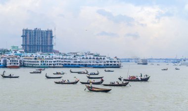 Dhaka 'daki Buriganga nehri üzerindeki Sadarghat nehir limanının güzel manzarası. Nehirde bulutlu bir arka planı olan feribotlar..