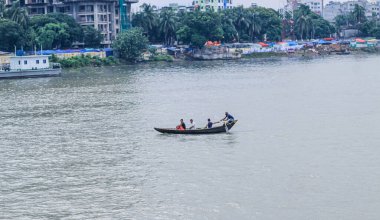 Dhaka 'daki Buriganga nehri üzerindeki Sadarghat nehir limanının güzel manzarası. Nehirde bulutlu bir arka planı olan feribotlar..