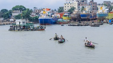 Dhaka 'daki Buriganga nehri üzerindeki Sadarghat nehir limanının güzel manzarası. Nehirde bulutlu bir arka planı olan feribotlar..