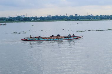 Dhaka 'daki Buriganga nehri üzerindeki Sadarghat nehir limanının güzel manzarası. Nehirde bulutlu bir arka planı olan feribotlar..
