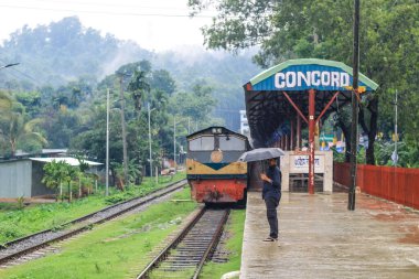 İnsanlar yağmurda tren için bekliyor. Yağmurlu bir tren istasyonu. Chittagong Üniversitesi, Bangladeş tren istasyonu.