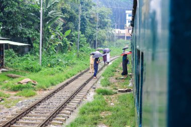 İnsanlar yağmurda tren için bekliyor. Yağmurlu bir tren istasyonu. Chittagong Üniversitesi, Bangladeş tren istasyonu.