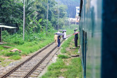 İnsanlar yağmurda tren için bekliyor. Yağmurlu bir tren istasyonu. Chittagong Üniversitesi, Bangladeş tren istasyonu.