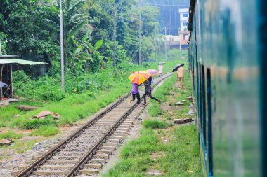 İnsanlar yağmurda tren için bekliyor. Yağmurlu bir tren istasyonu. Chittagong Üniversitesi, Bangladeş tren istasyonu.