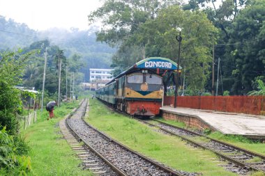 İnsanlar yağmurda tren için bekliyor. Yağmurlu bir tren istasyonu. Chittagong Üniversitesi, Bangladeş tren istasyonu.