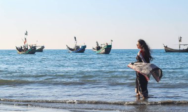 Plajda siyah sari giyen genç kadınlar. Geleneksel Hint sarisiyle kayaların arasında özgürlüğün ve gün batımının ya da güneşin tadını çıkaran bir kız. Kumsalda sari giyen güzel bir Hintli kadın..