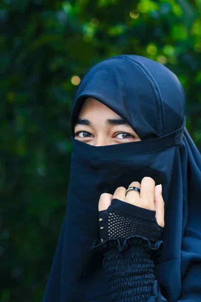 Closeup of beautiful woman face covered with hijab. Perfect shiny eyes of a Muslim girl. Young niqab girl portrait with the background.