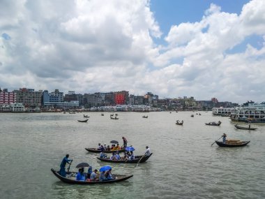Dhaka 'daki Buriganga nehri üzerindeki Sadarghat nehir limanının güzel manzarası. Nehirde bulutlu bir arka planı olan feribotlar..