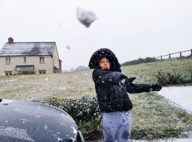 Çocuk kış mevsiminde kameraya kar taneleri atıyor.