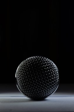 Close up shot of a microphone head on a white table with black background and copy space.