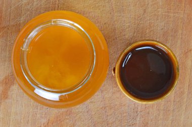 Fresh natural organic honey pictured in a jar and a rustic cup.