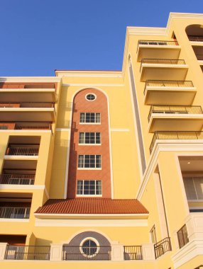 Güzel mimari. Güneş ışığı sarı bir evin ön cephesine düşer. Kullanım dışı pencere ve balkonlar