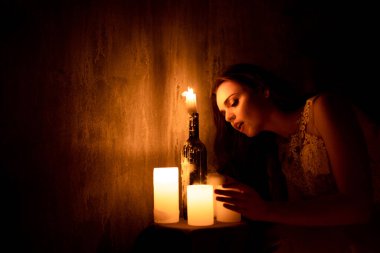 Bir kadın mum ışığında bir odada oturuyor. Genç bir kız yanan mumlara bakar ve nişanlısına şaşar.