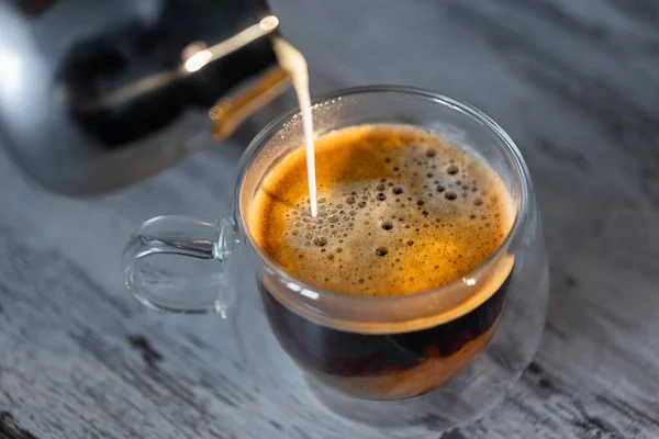 牛乳で満たされたコーヒーのカップ 暖かい牛乳が朝のコーヒーに注がれる ストックフォト