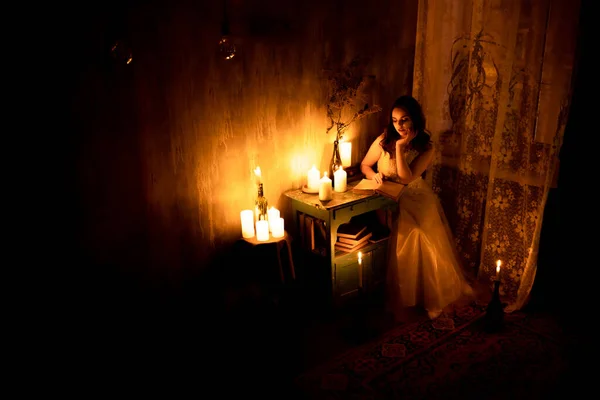 女の子は部屋の隅に座り ろうそくの明かりで読み上げます キャンドルライト トップビュー ストック写真