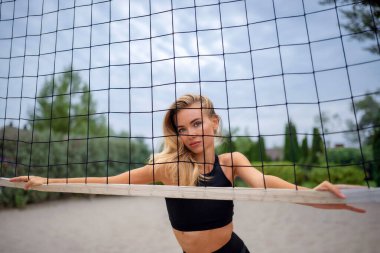 Genç atletik kadın voleybol ağının yanında ısınıyor..