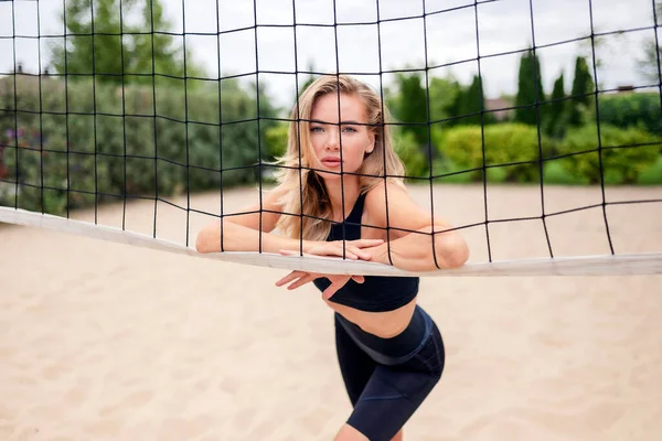 在沙滩排球网旁边摆姿势的年轻女运动员 — 图库照片