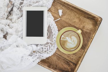Kahve tepsisi, dantel ve fotokopi alanı olan e-kitap. Güneşli bir sabahta yatakta kahvaltı..