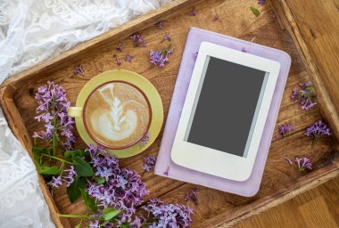 Yaz ya da bahar ev kompozisyonu dantelli, çiçek açan mor leylak dalları, fotokopi alanı ve kahve dolu e-kitap. Kadınsı blog sosyal medya şablonu.