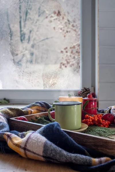 A cup of winter tea near the window. A hot drink for winter cold snowy days. Winter mood and cozy home concept. Soft focus.