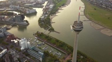 Almanya 'nın Düsseldorf kentindeki Ren Nehri' nin yanında gün doğumu. Nehir kenarındaki Skyline binalarına bakan ikonik rheinturm 'un hava görüntüsü.