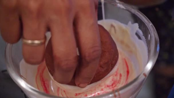 Baker Tremper le beignet dans le bol avec glaçage blanc et rose. gros plan — Video