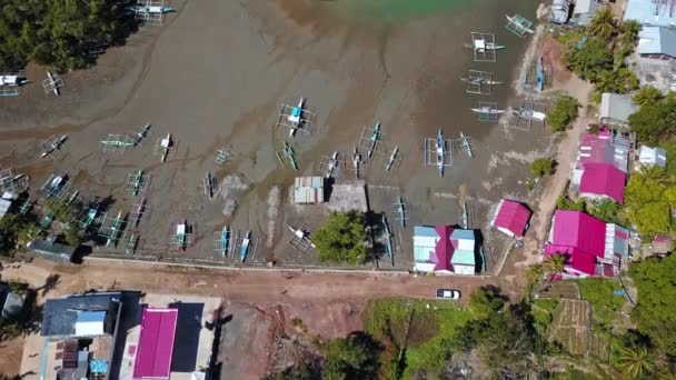 Tradiční lodě na pobřeží ostrova s scénickým Seascape v pozadí na ostrově Palawan, Filipíny. - Letecký naklápěcí výstřel — Stock video