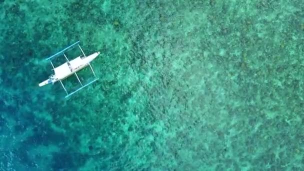 Традиційний підводний човен, що плаває через гірський пляж з кораловими рифами на задньому плані. повітряний дрон — стокове відео