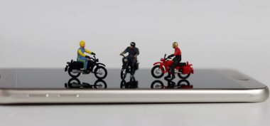Akıllı telefonda üç tane minyatür motosiklet sürücüsü. Kullanışlı çevrimiçi dağıtım kavramı.