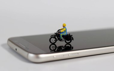 Akıllı telefondaki minyatür bir motosiklet sürücüsü. Kullanışlı çevrimiçi dağıtım kavramı.