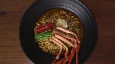 Kırmızı yengeçle pişirilmiş baharatlı ramen. Siyah kasede dönen kırmızı yengeç..