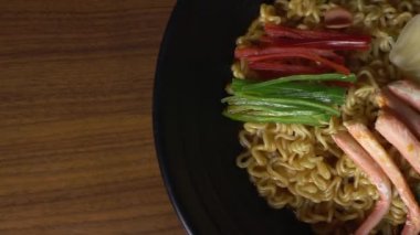 Kırmızı yengeçle pişirilmiş baharatlı ramen. Siyah kasede dönen kırmızı yengeç..