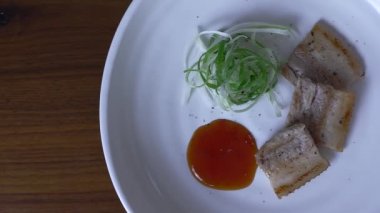 Beyaz tabakta ızgara domuz göbeği. Izgara domuz eti ve baharatlı soğan. Alkol için meze olarak çok popülerdir..