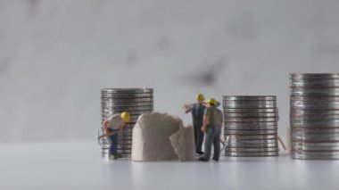 Maaş ve iş gücü konsepti. Çalışan minyatür işçiler ve bozuk para yığınları.