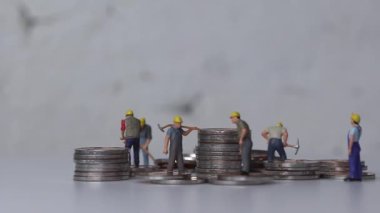 Maaş ve iş gücü konsepti. Madeni para yığınlarıyla çalışan minyatür işçiler.