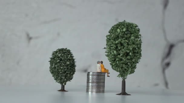 年迈的迷你人在一堆堆小树之间的硬币上 老龄化社会的概念和不断上升的社会成本 — 图库视频影像