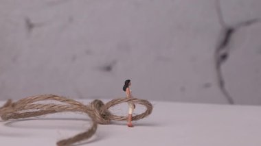 Toplumda kariyer çöküşü yaşayan kadın sorununa dair bir kavram. İple bağlanmış minyatür bir kadın..