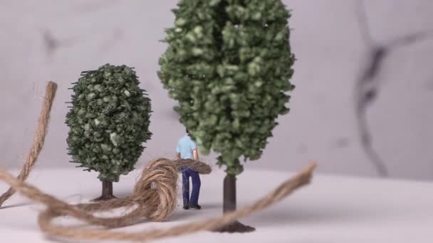 Ein Miniaturmann Der Einen Miniaturbaum Und Ein Seil Gebunden Ist — Stockvideo