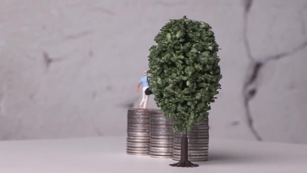迷你高尔夫球手站在一堆硬币和一棵微型树上 带有商业概念的微型硬币和成堆的硬币 — 图库视频影像