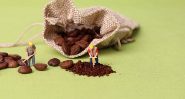 Kahve çekirdekleri ve iki minyatür işçi. İş konsepti olan minyatür insanlar.