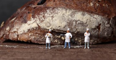 Kızarmış ekmek ve üç tane minyatür şef. Minyatür insanlar ve iş konsepti.