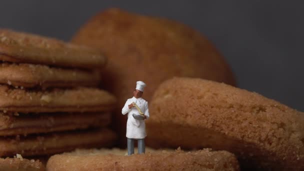 サクサククッキーの上に立つミニチュアシェフ ミニチュア人とビジネスコンセプト — ストック動画