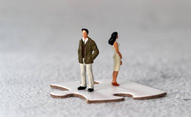 Miniature people standing on puzzle pieces. The concept of gender conflict.