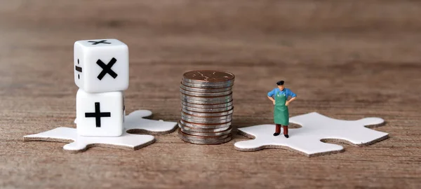 White puzzle pieces and miniature people with business concept. Pile of coins and a miniature man standing on a puzzle.