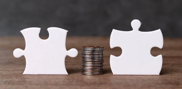 White puzzle pieces and pile of coin with business concept. A pile of coins between two pieces of puzzle.