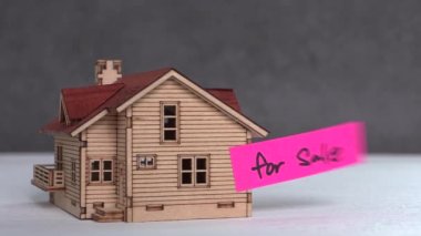'for sale' text on paper with a miniature house. Miniature house with business concept.