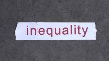A piece of paper that says inequality. The IN text on paper blew away in the wind.